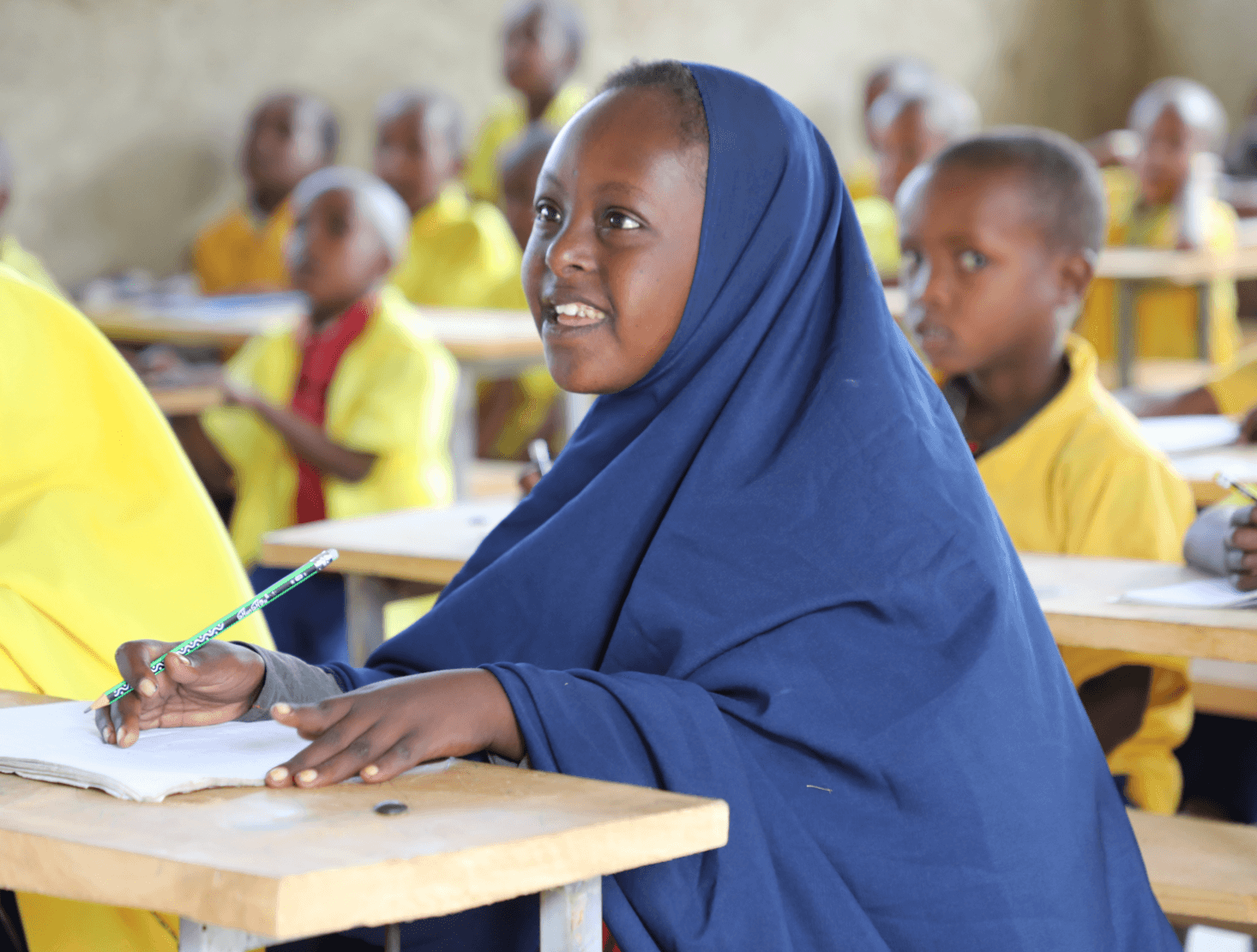 Smiling student sitting at a desk with a pencil and paper