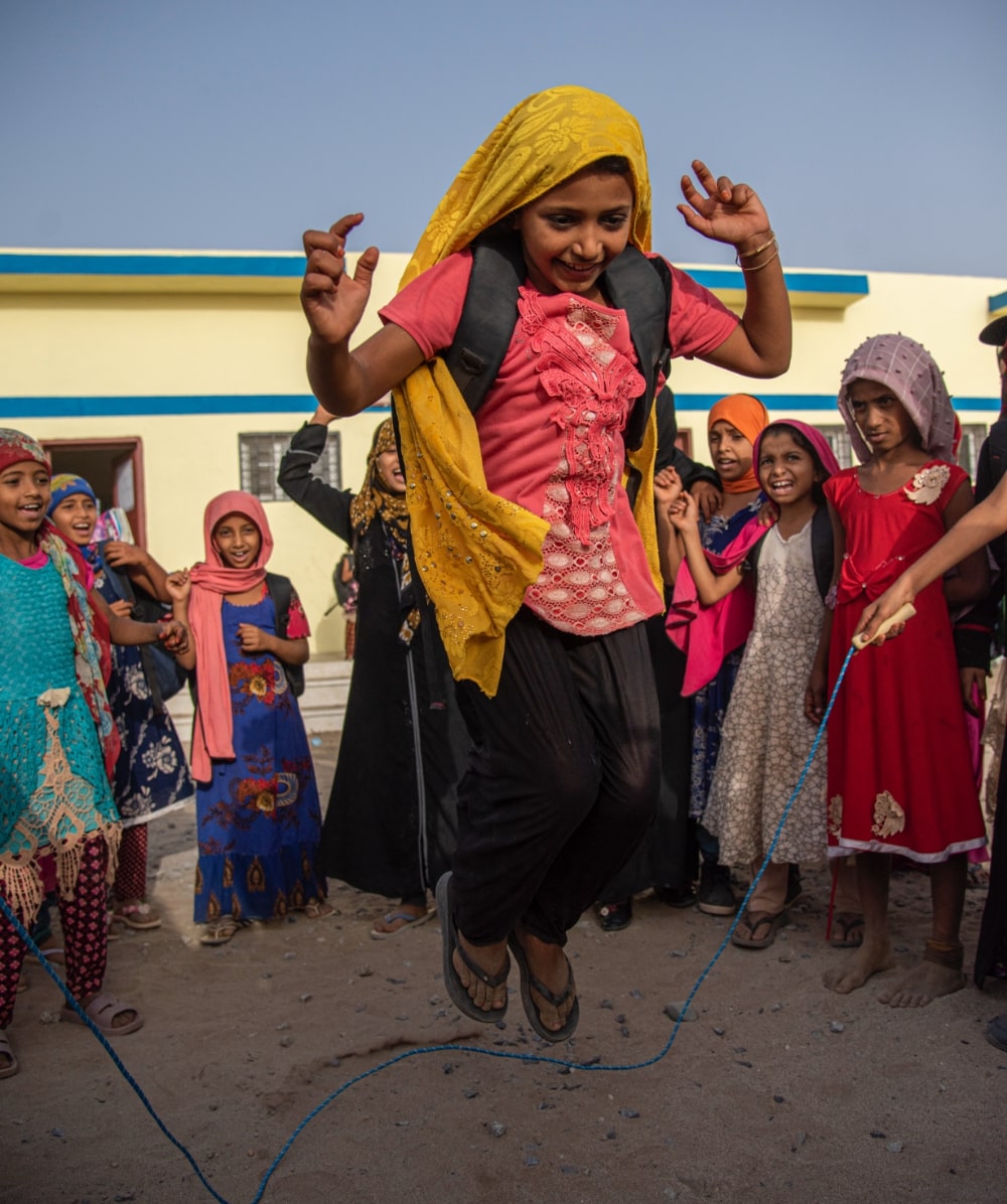 Radia jumping rope outside with her classmates