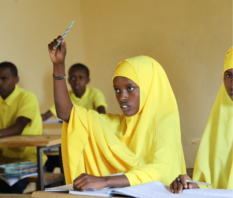 Hanifa in a classroom raising her hand