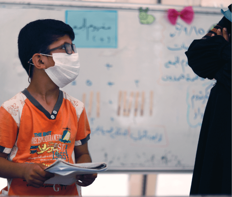 Rafat holding his notebook in the classroom