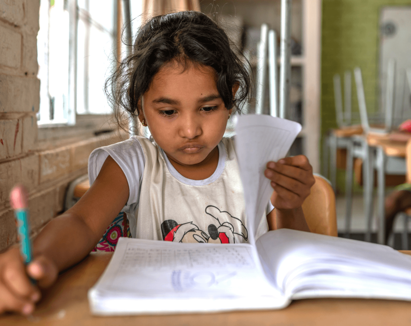 A student at her desk holding a pencil and reading a workbook