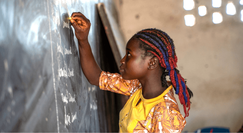 A student in a yellow shirt writing on the chalkboard