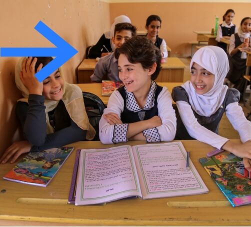 girls in their classroom sitting at a table smiling and laughing