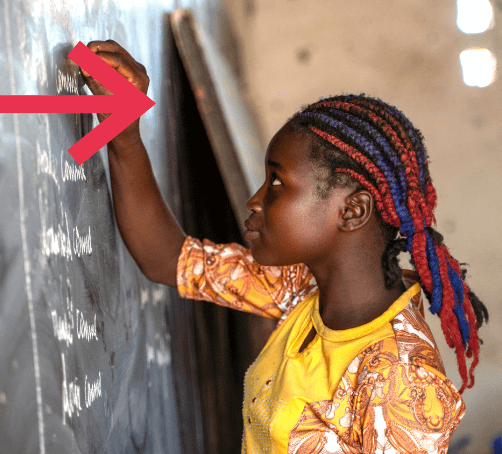 a girl in a yellow shirt writing on the chalkboard