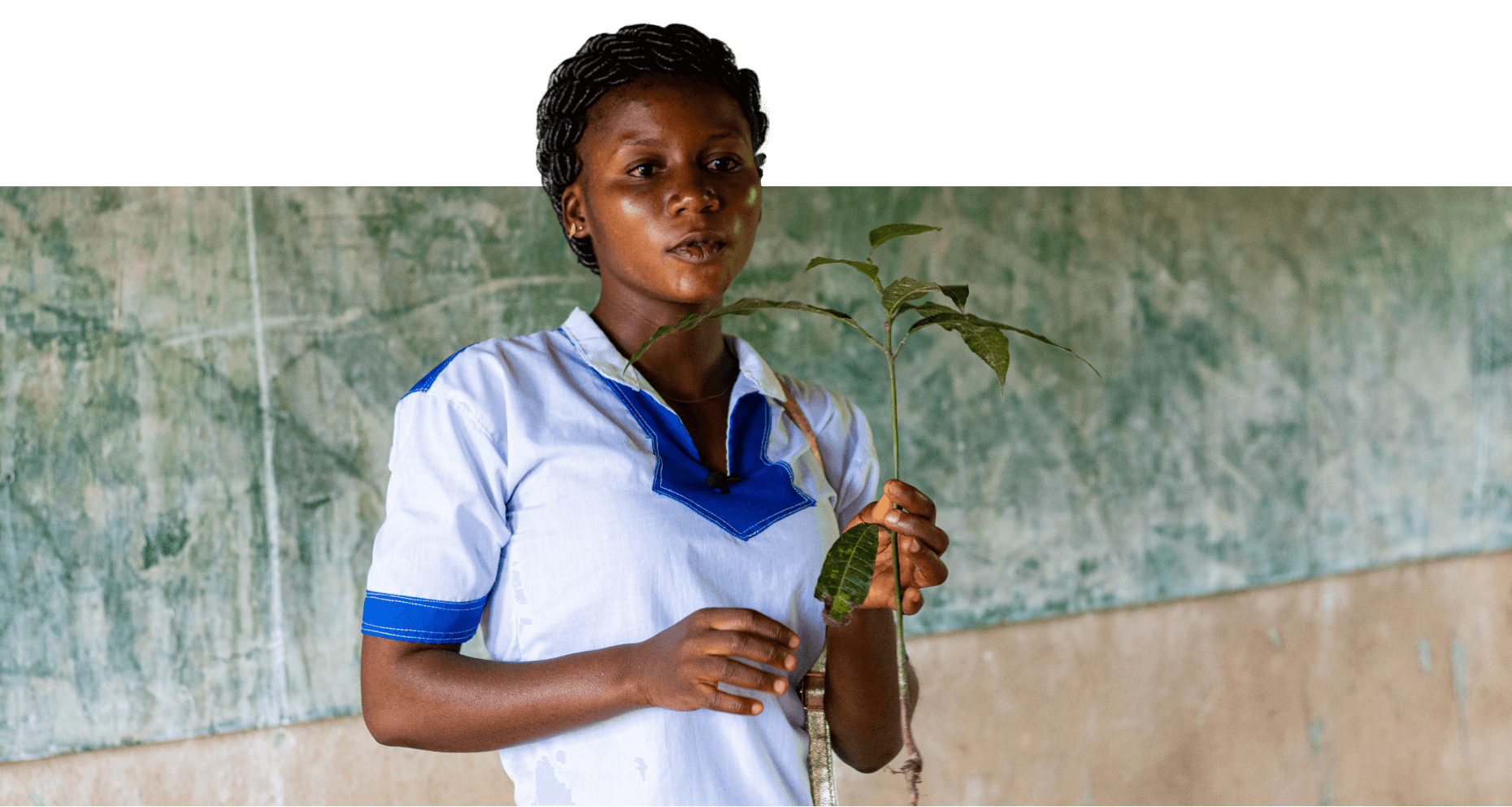 Meda talking in front of her class holding a plant