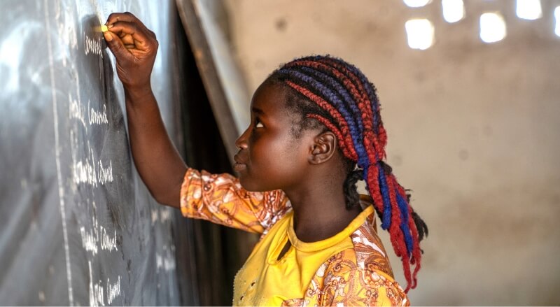 A student in a yellow shirt writing on the chalkboard