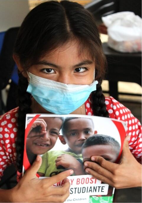 Sammy from Colombia wearing a mask and holding a workbook