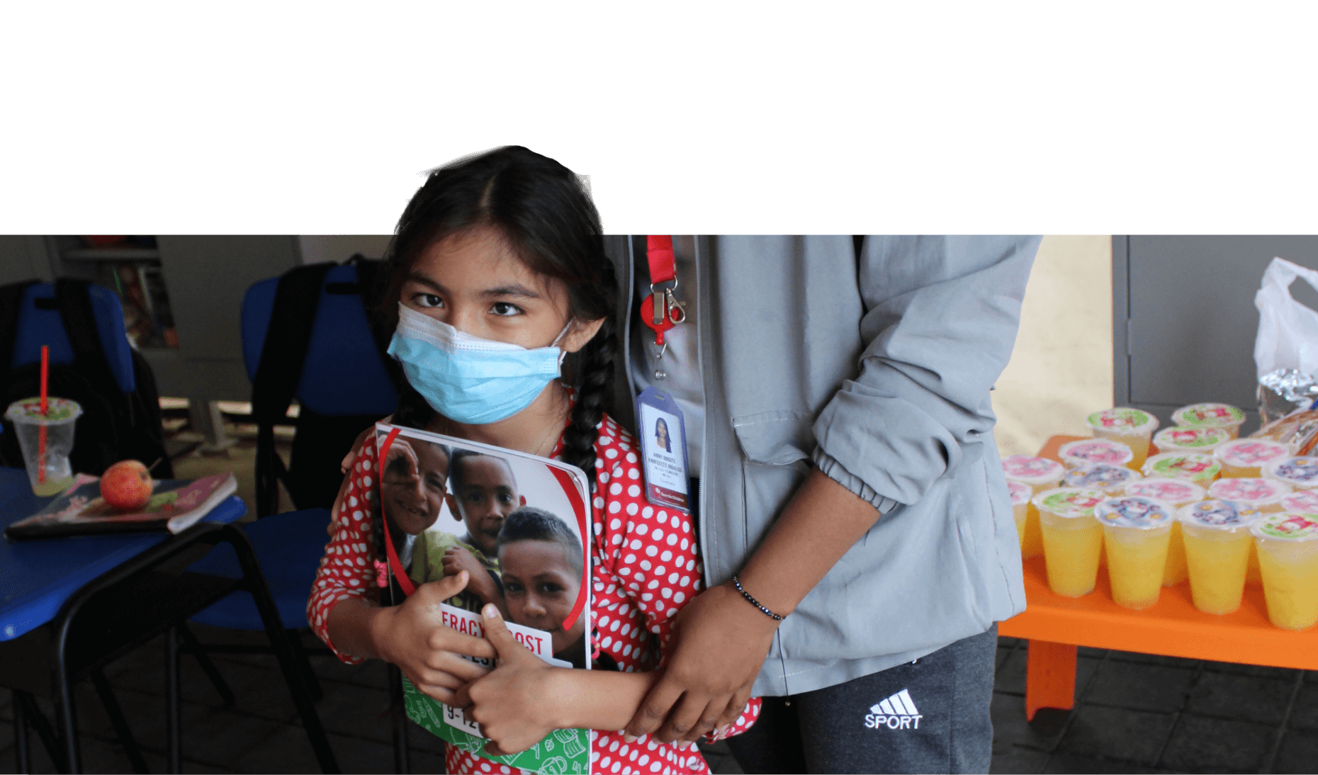 Sammy along with one other person wearing a mask and holding a workbook.