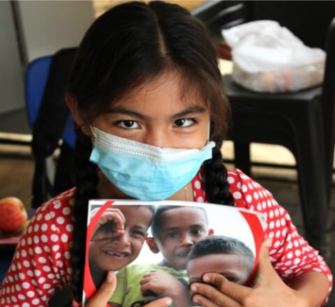 Sammy from Colombia wearing a mask and holding a workbook