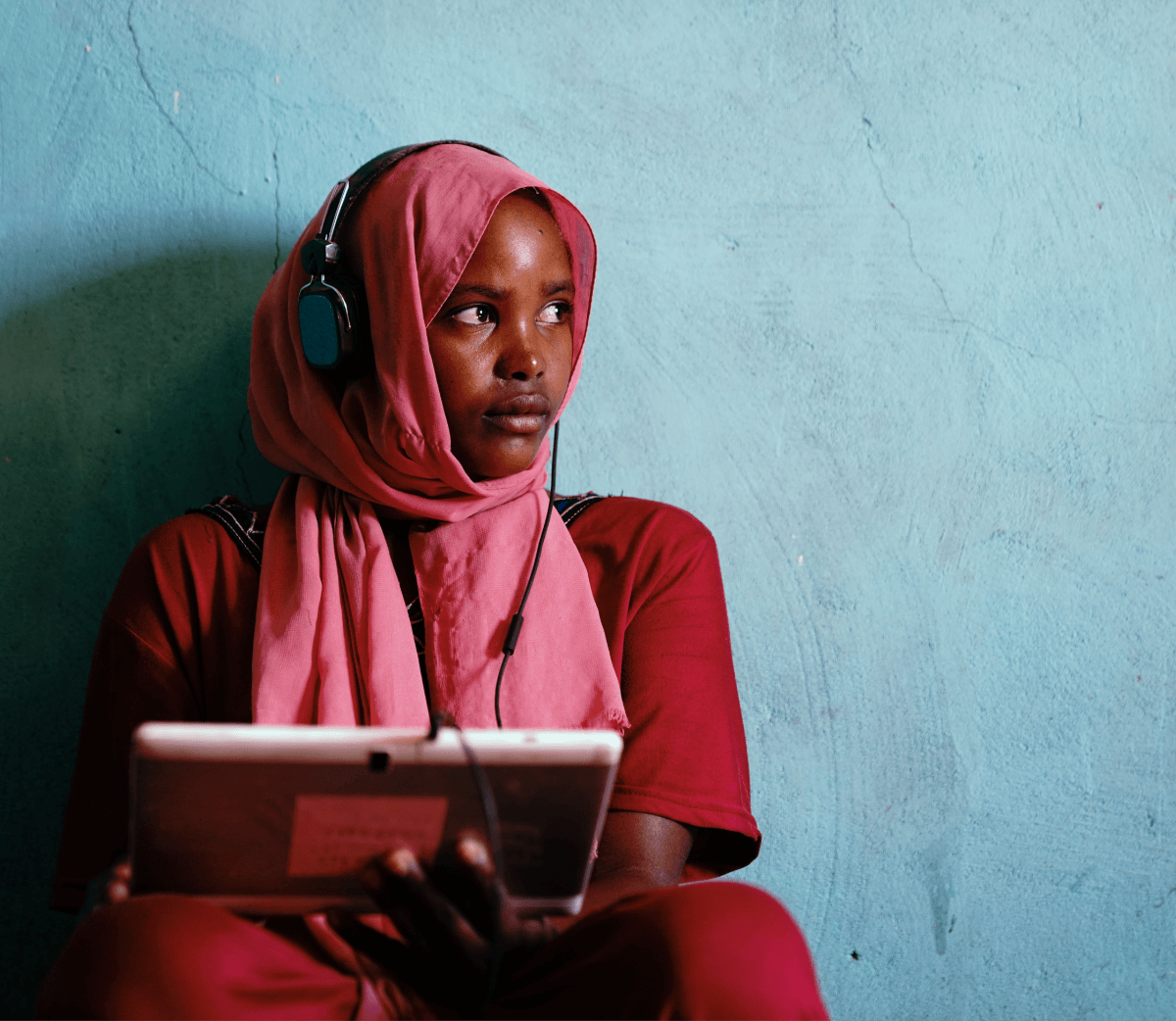A student sitting with headphones listening to educational materials on her tablet