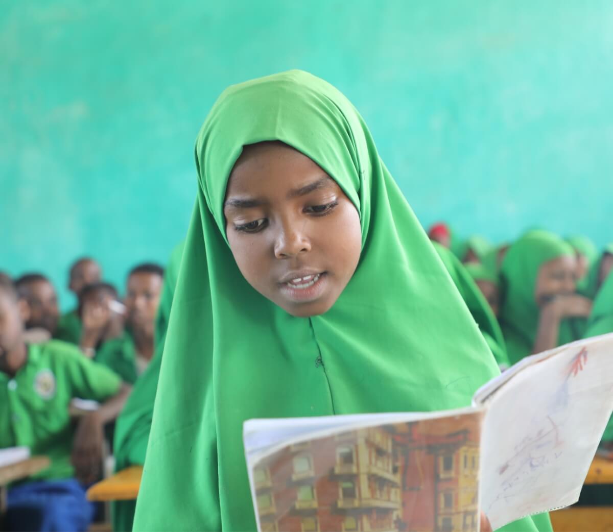 A student wearing green reading from her notebook