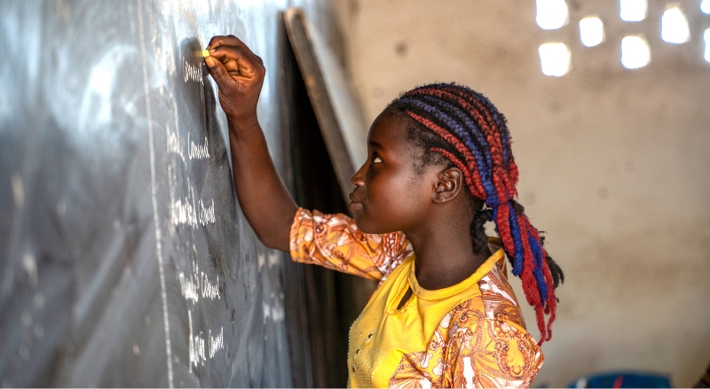 A student in a yellow shirt writing on the chalkboard