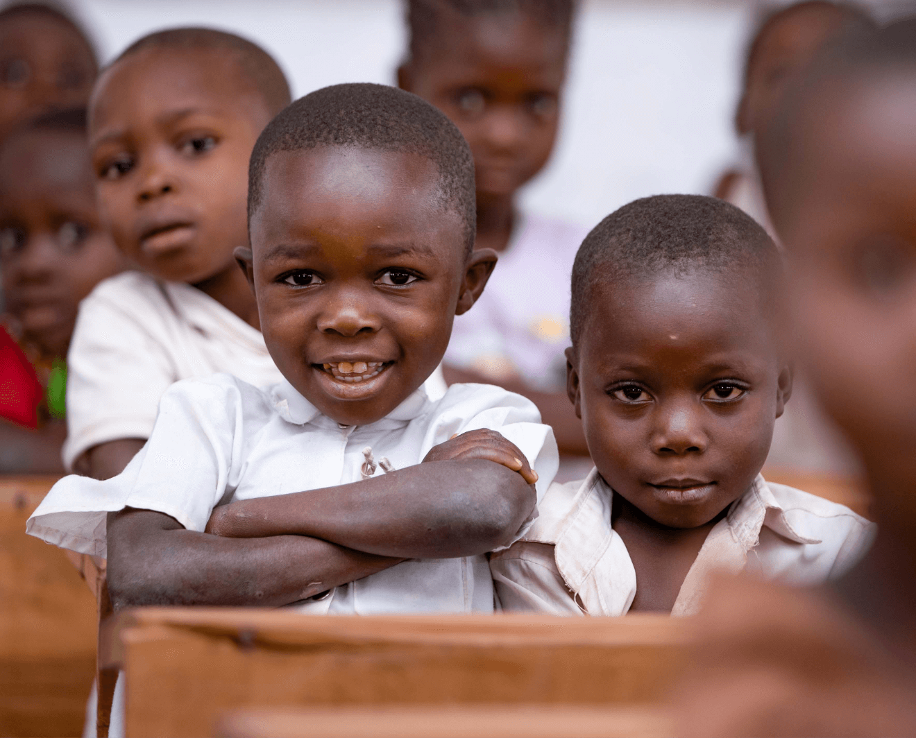 Boys wearing white shirts in their classroom smiling and posing for the camera