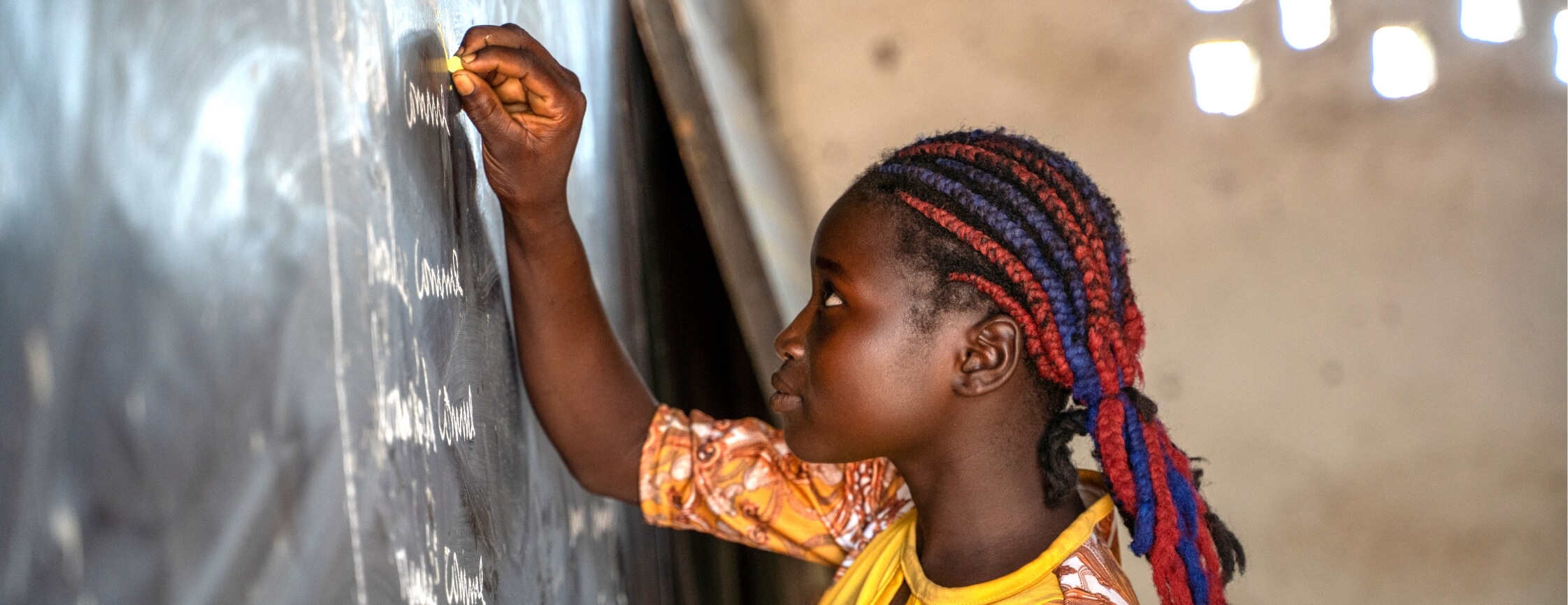 A student in a yellow shirt writing on the chalkboard