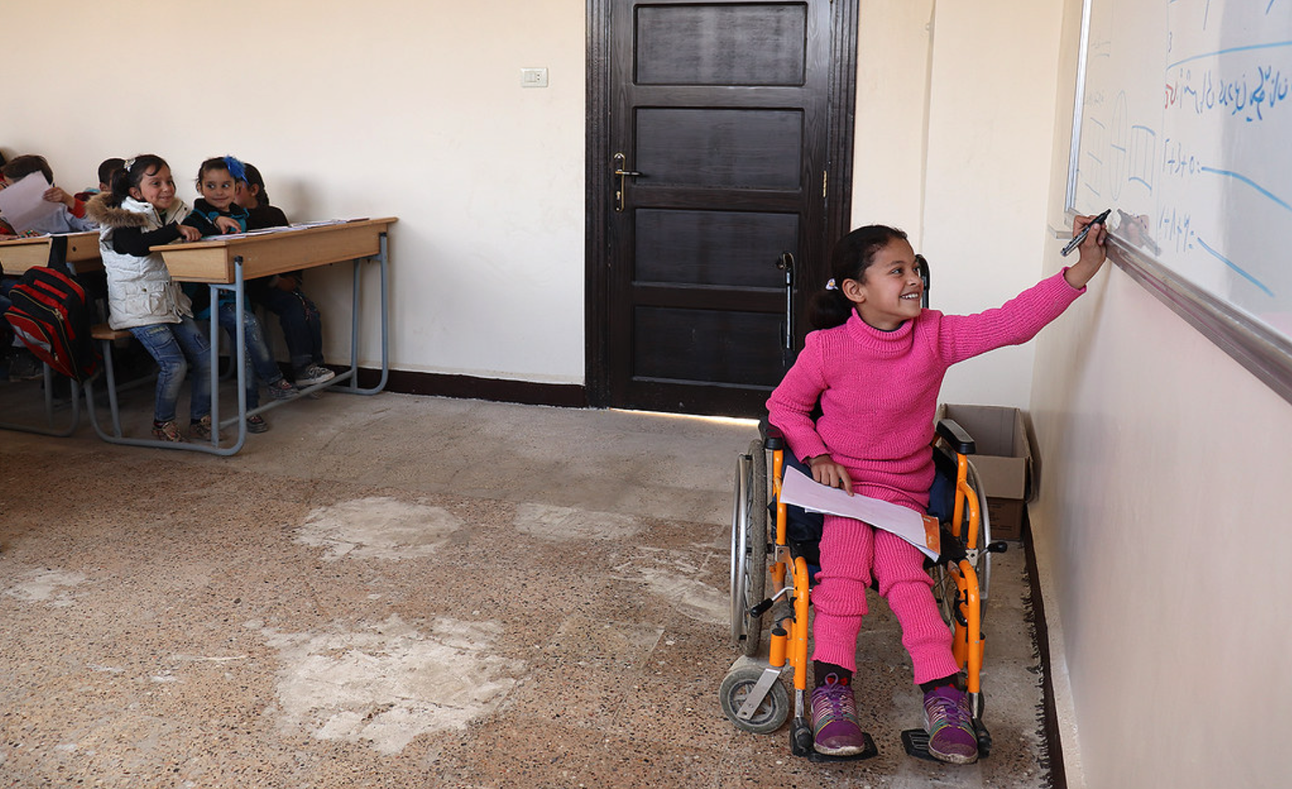 Girl in a wheelchair in Syria writing on the board. Girl in a wheelchair in Syria writing on the board.