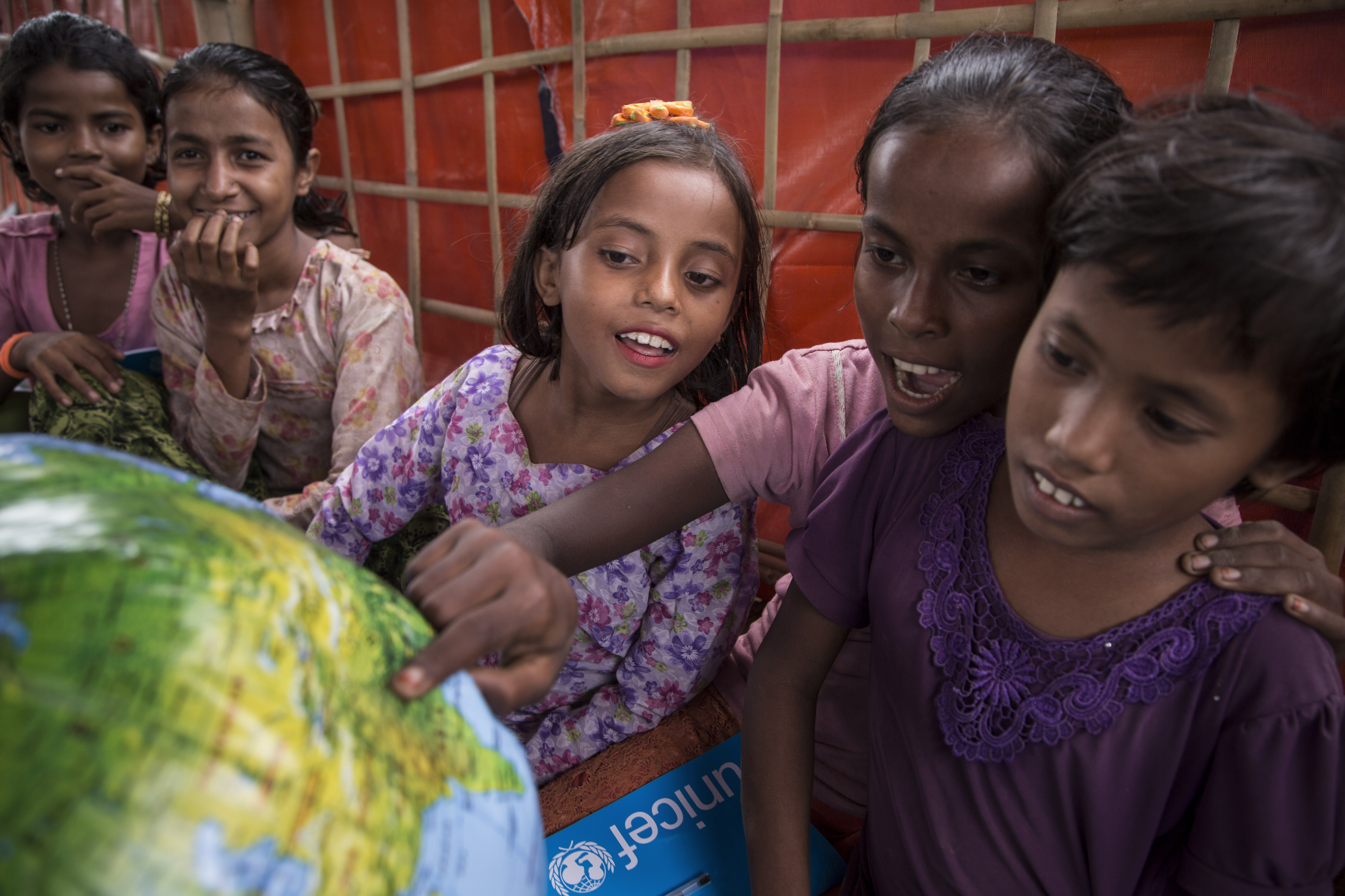 Children pointing out a world atlas
