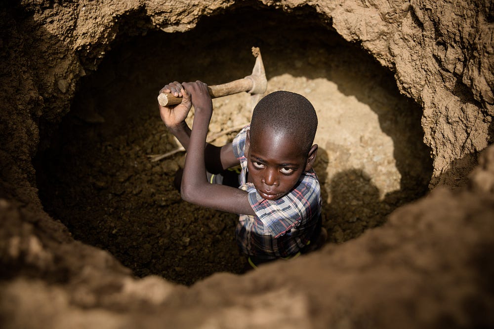 Young boy digging in a hole.