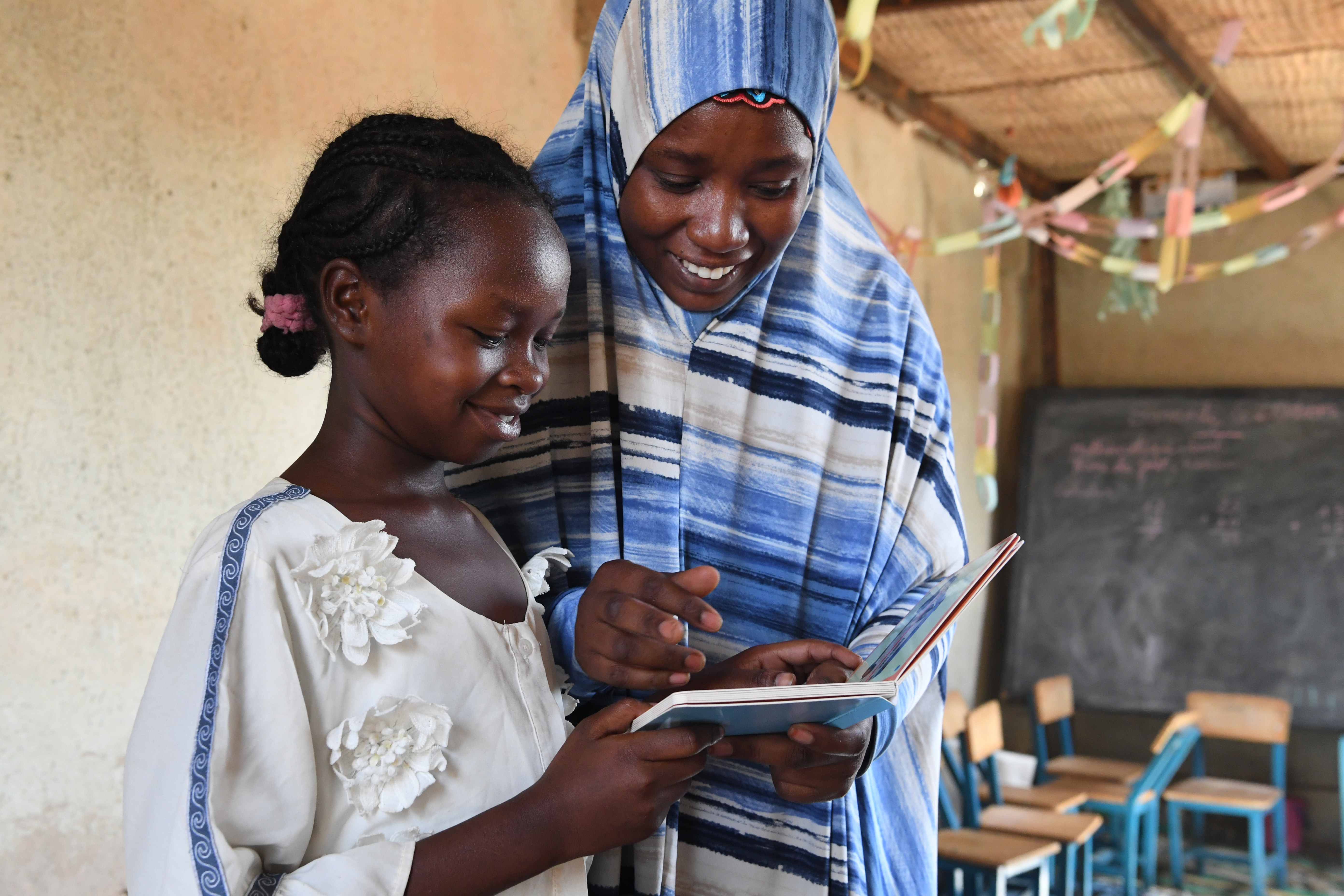 Teacher and student look at book together.