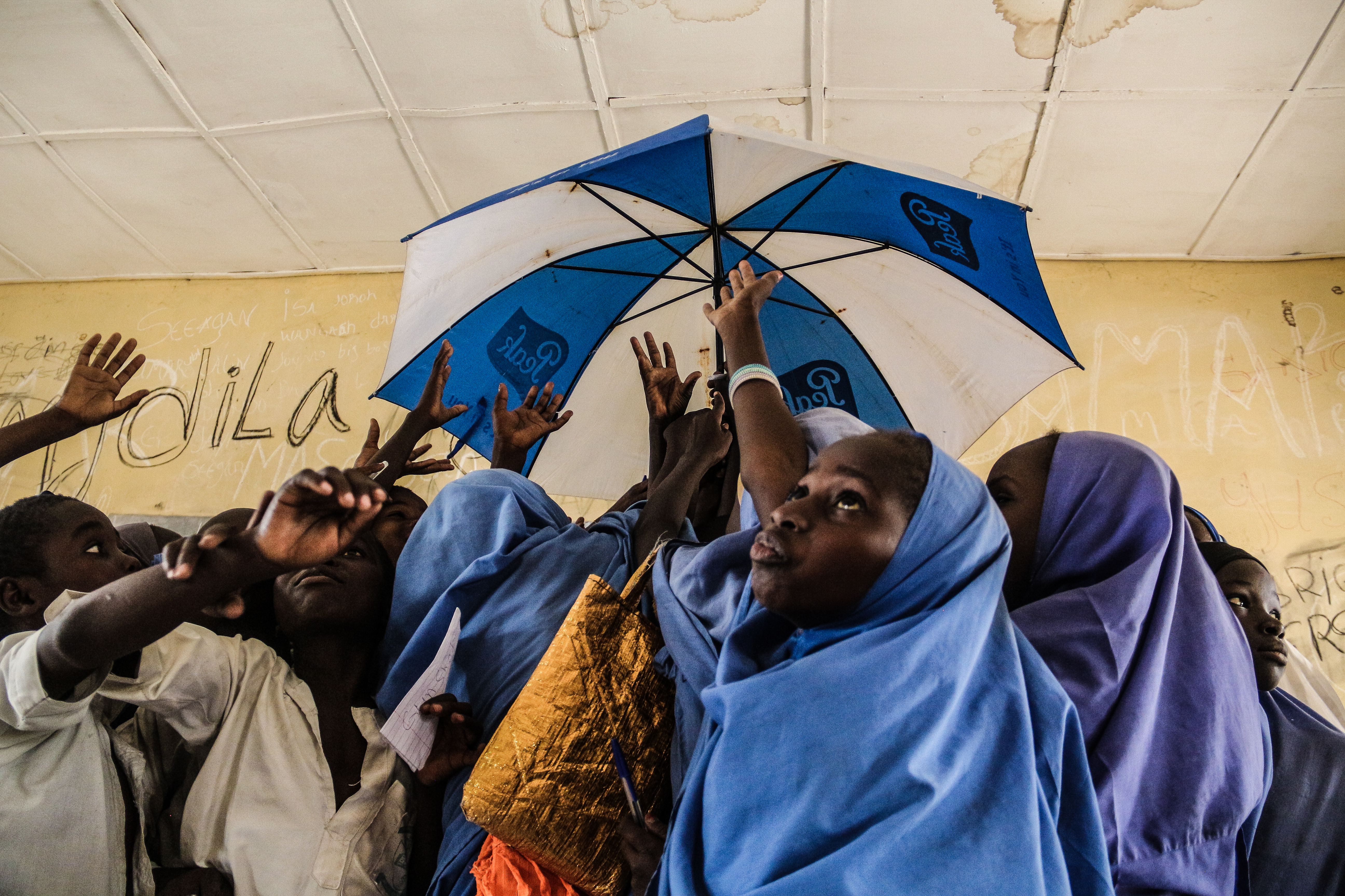 Students in a classroom in Nigeria hold up an umbrella.