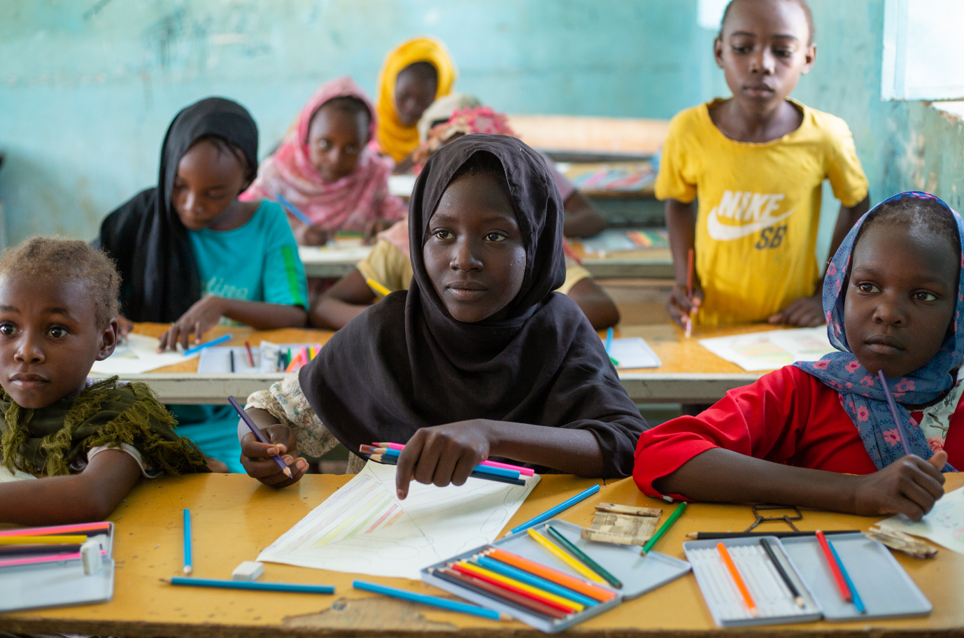 Girls inside a classroom colouring books