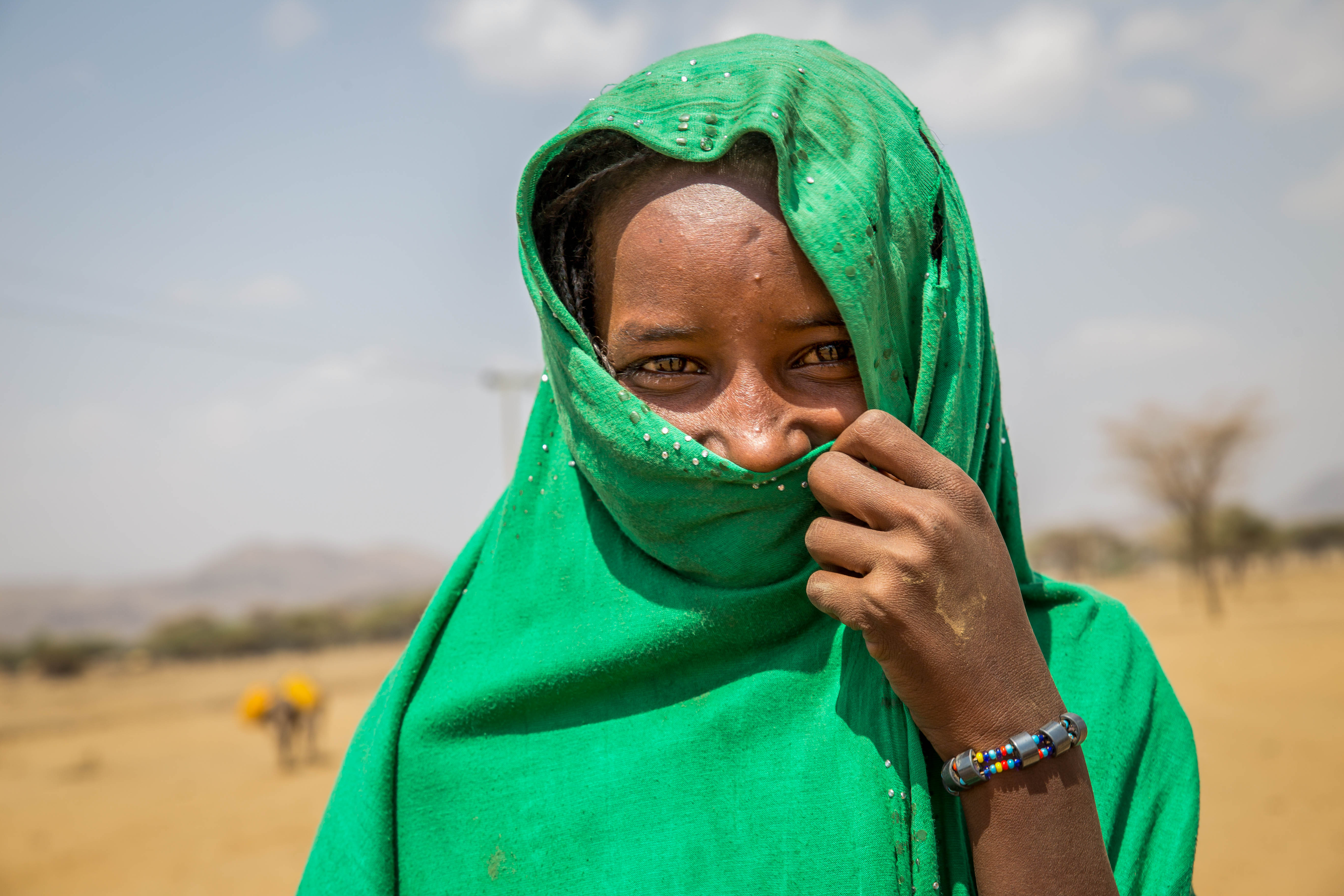 Girl smiling and covering half of her face with a scarf