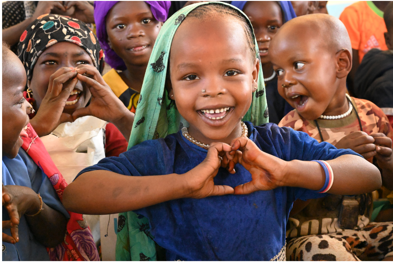 Girl in classroom making a heart shape with her hands