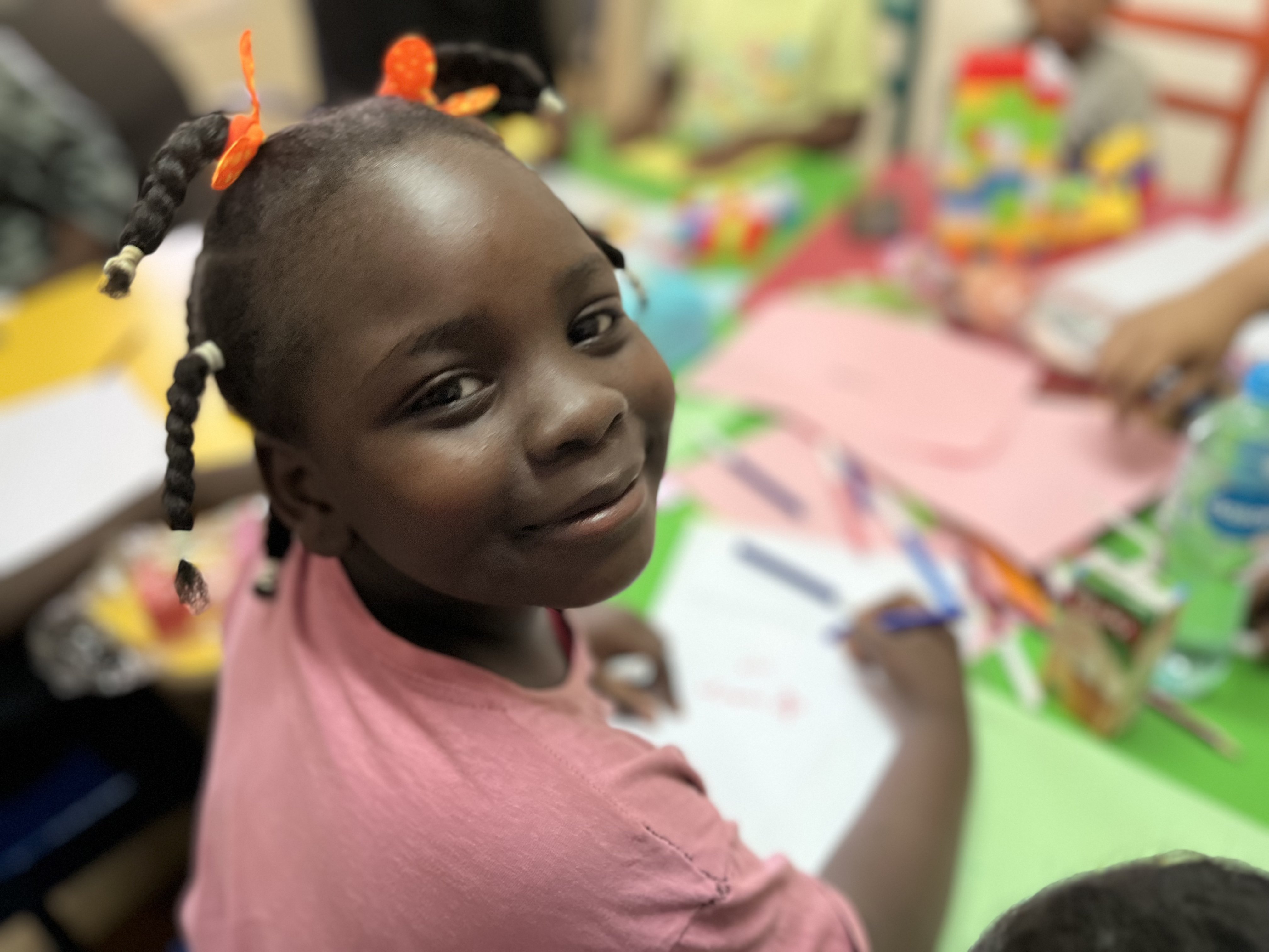 Sudanese refugee girl smiles in classroom in Egypt.