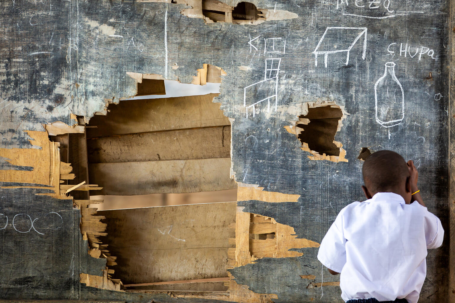 Children writing on an impacted blackboard