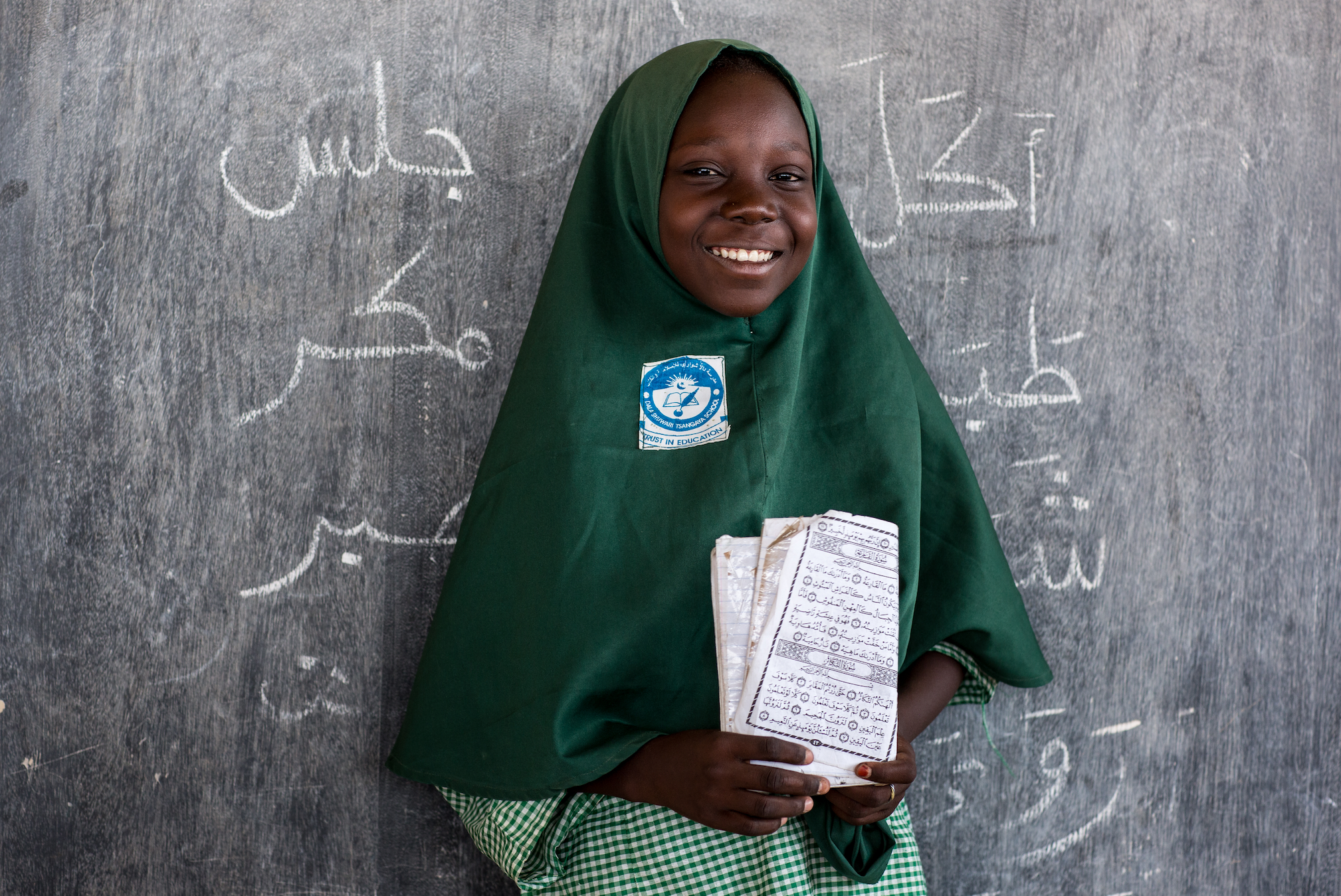 Happy Nigerian girl holding a book in a classroom