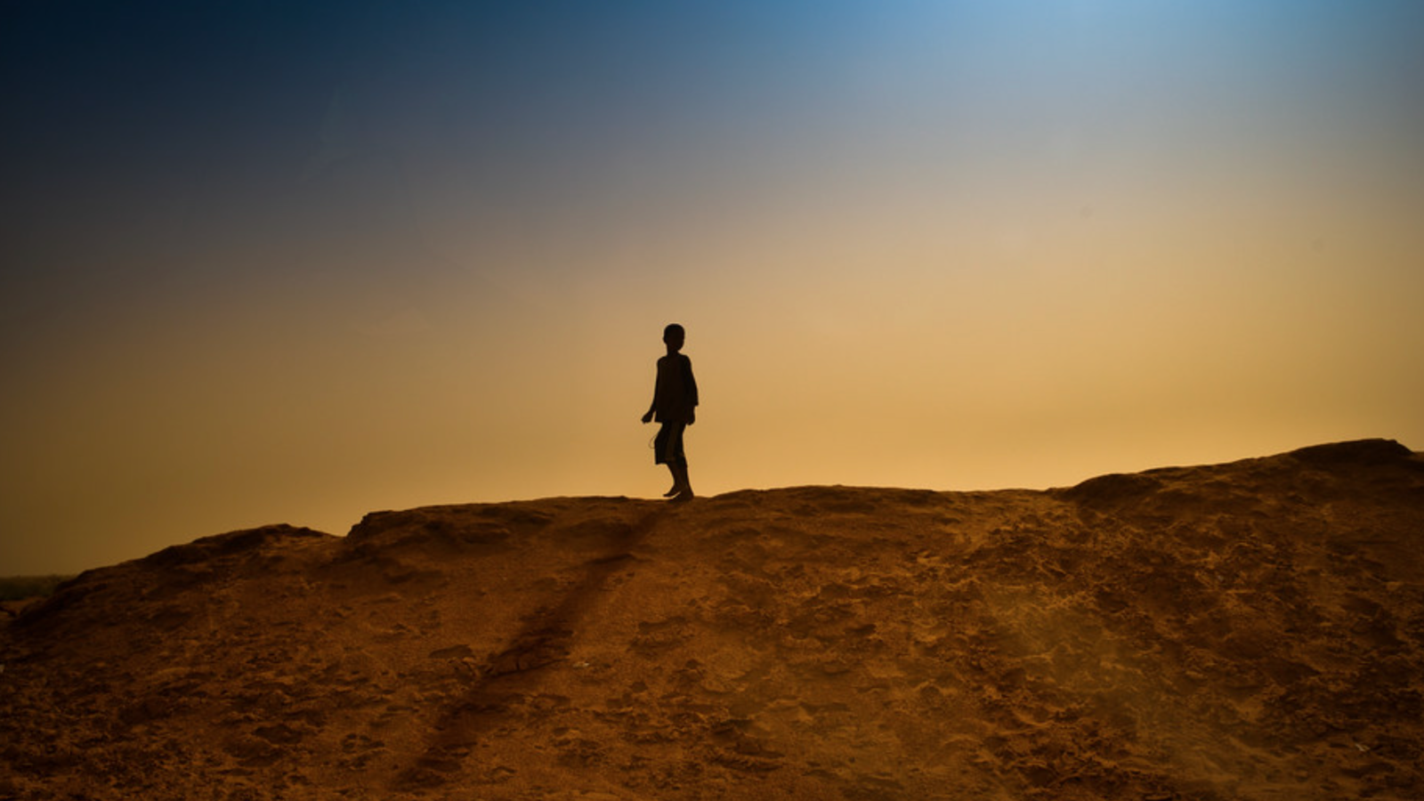 Child walking on a ridge outside.