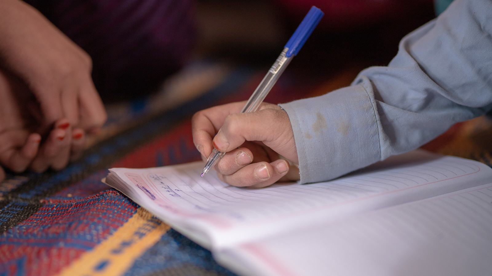 child writing on notebook